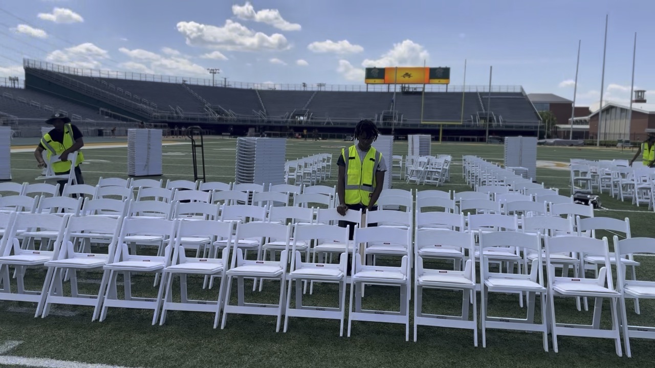 Party People Rentals crew arranging rows of white chairs at an outdoor stadium