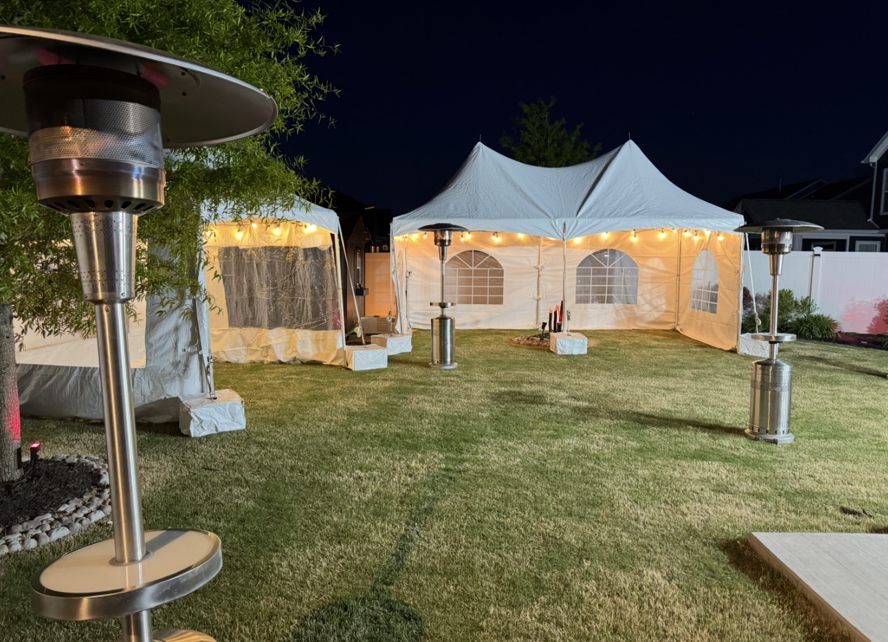 White event tents glowing with warm lights at an evening celebration